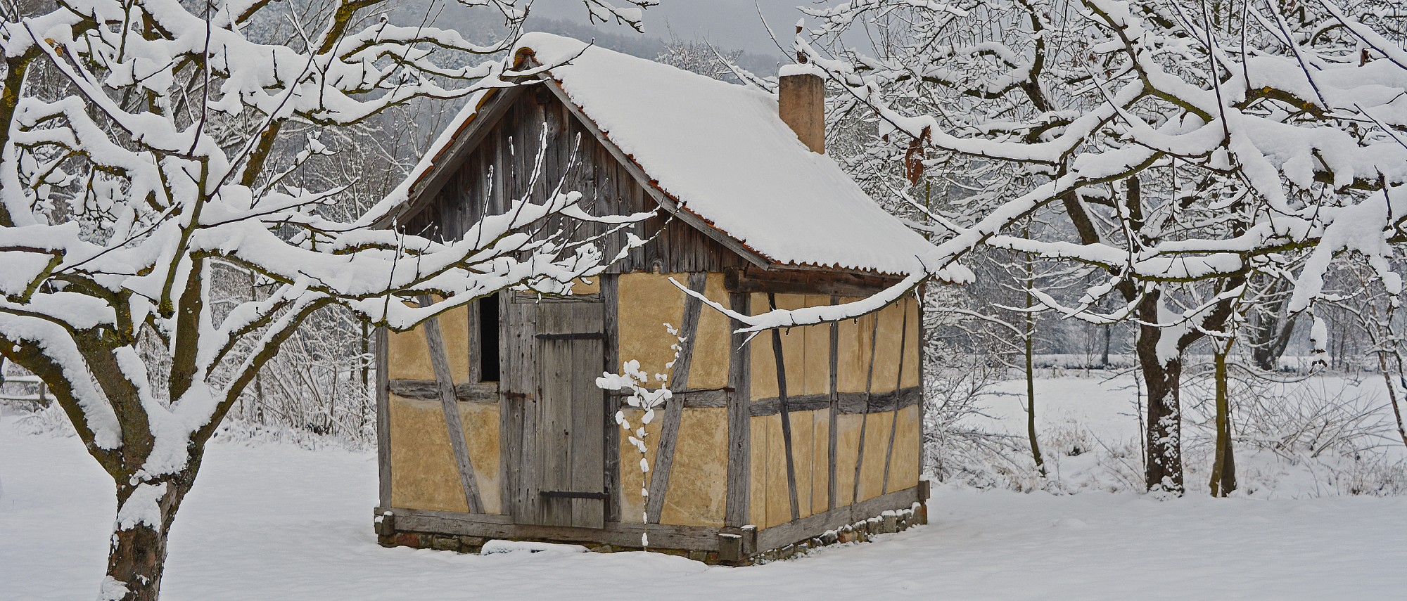 kleines Fachwerkgebäude in verschneiter Landschaft