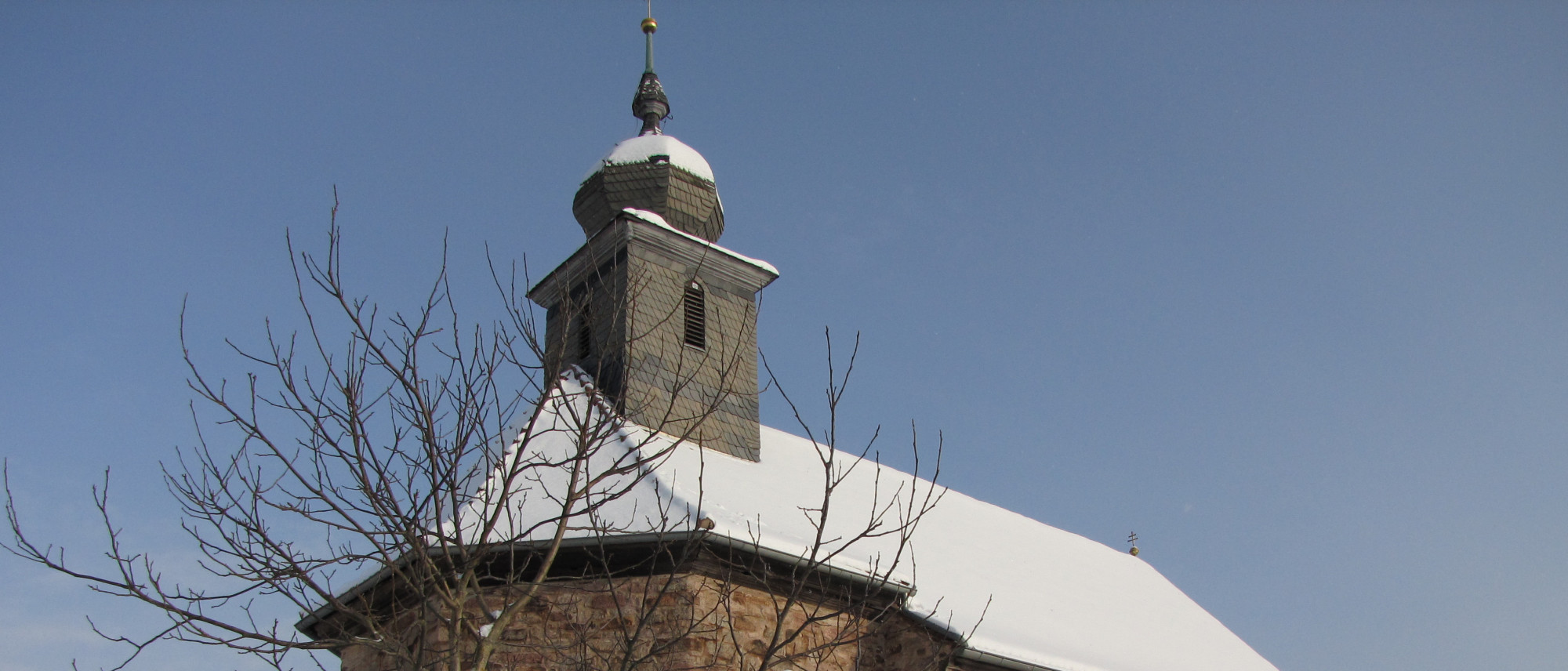 schneebedeckte Dach und Kirchturm einer Kirche