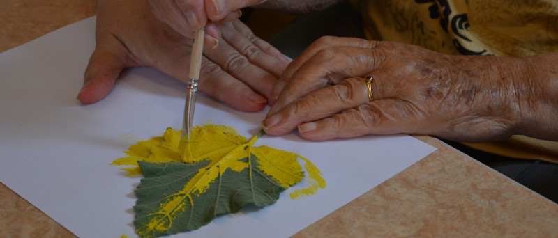 Detailaufnahme von Händen, die ein Blatt gelb anpinseln