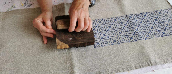 Druck eines blauen Musters mit einem Handmodel auf ein Leinentuch
