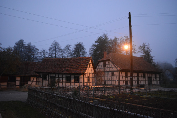 Fachwerkgeb&auml;ude bei D&auml;mmerung bei eingeschalteter Stra&szlig;enlaterne, im Vordergrund Gartenzaun