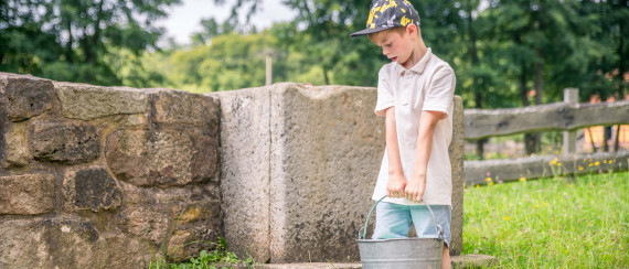 Junge hebt einen Blecheimer hoch