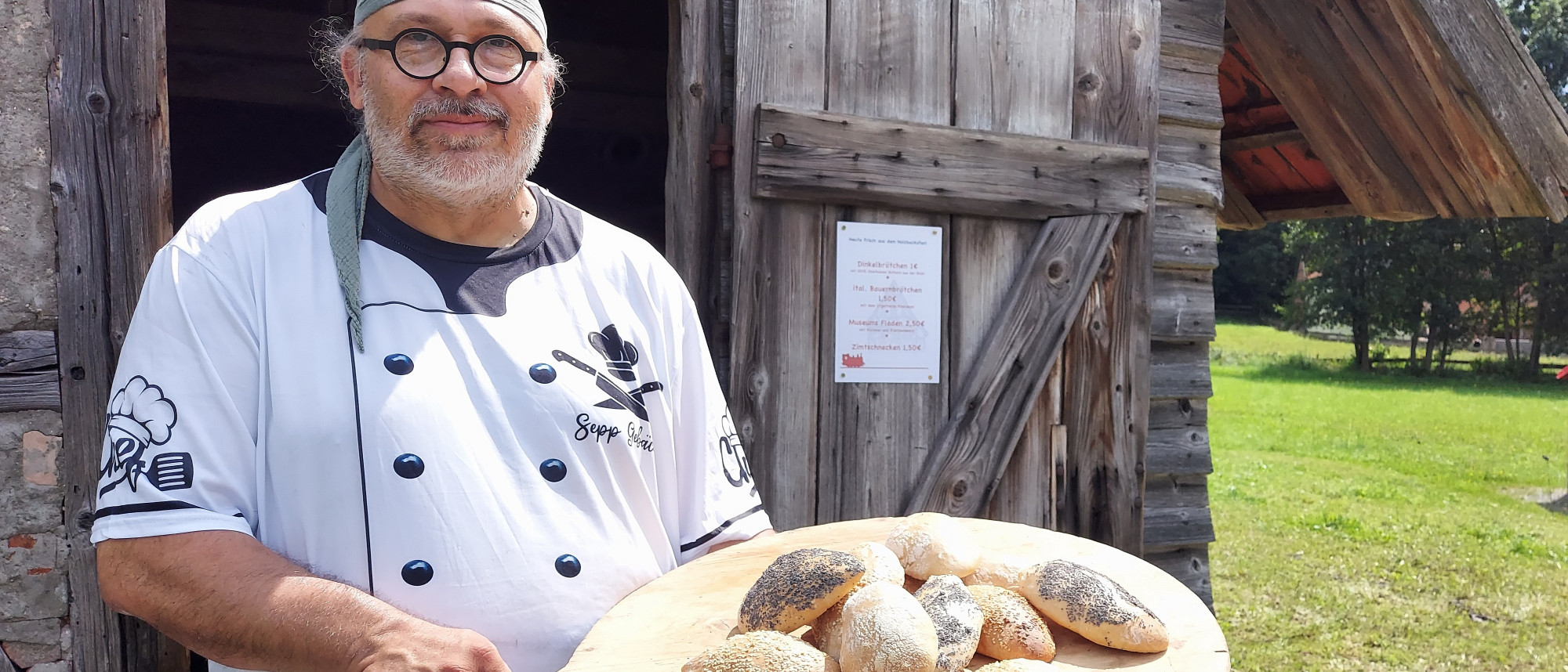 Mann hält Holzbrett mit Brötchen in der Hand