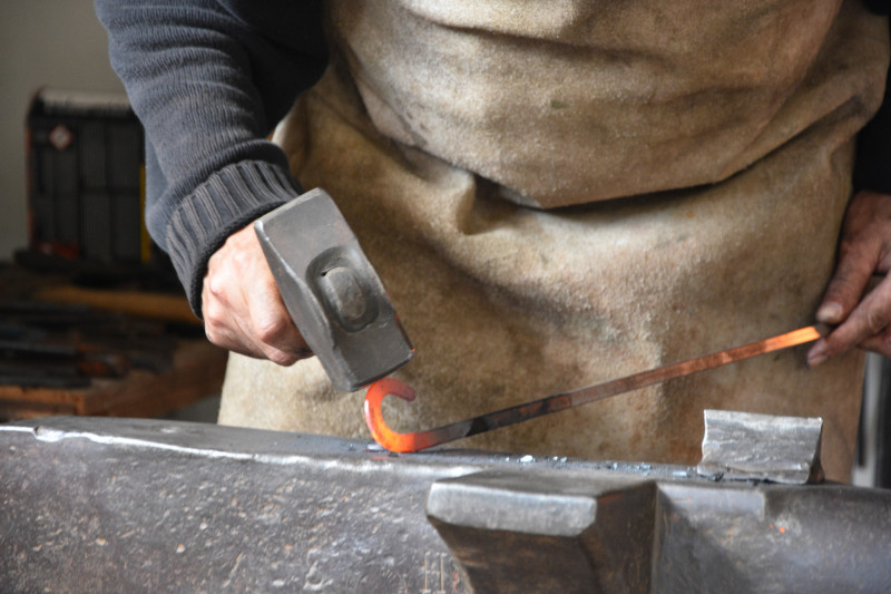 Gl&uuml;hendes Eisen wird von Hammer auf Amboss bearbeitet