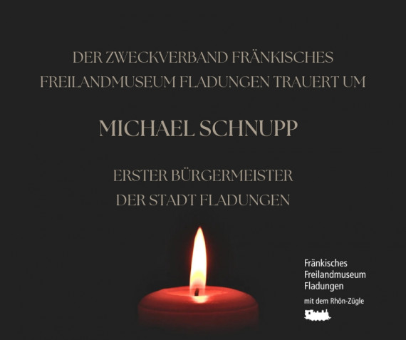 Text: Der Zweckverband Fränkisches Freilandmuseum Fladungen trauert um Michael Schnupp, Erster Bürgermeister der Stadt Fladungen, darunter brennende rote Kerze, rechts unten Logo Freilandmuseum, schwarzer Hintergrund