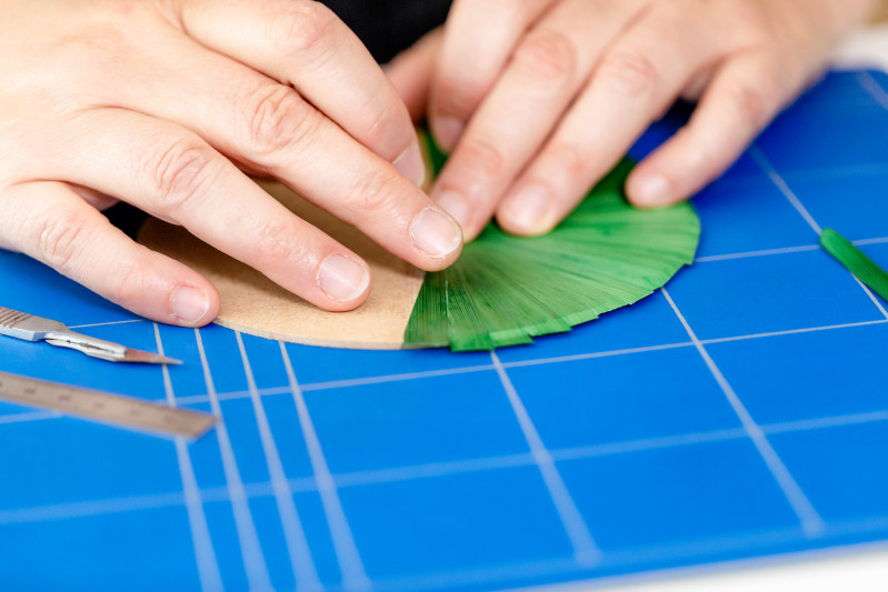 H&auml;nde arbeiten an einem Strohmarketerie-Werk