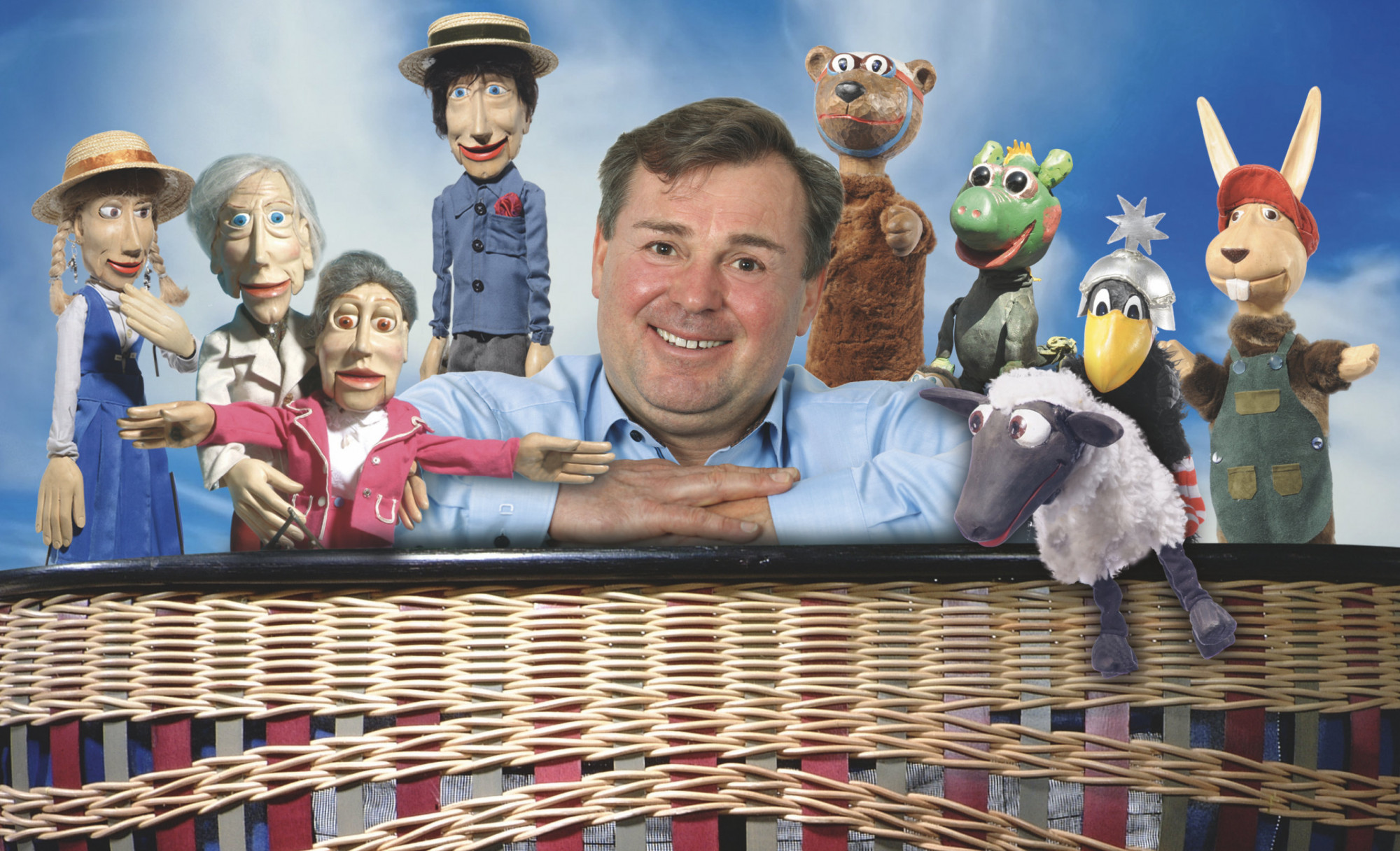 Mann lehnt auf einem Korb, umringt von Puppenfiguren