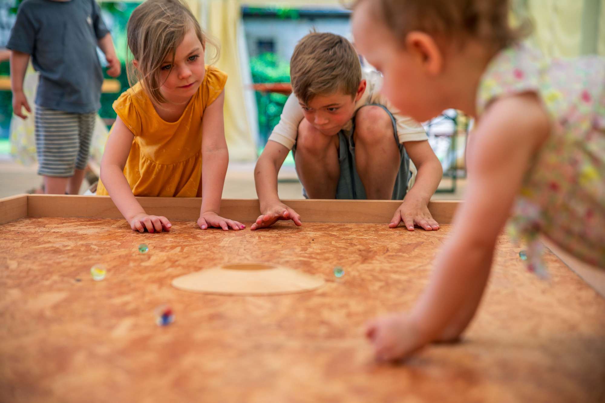 Drei Kinder spielen mit Murmeln