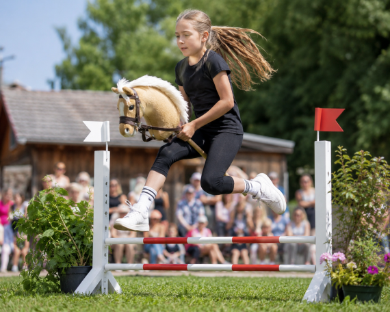 M&auml;dchen springt auf einem Hobby Horse &uuml;ber ein Hindernis