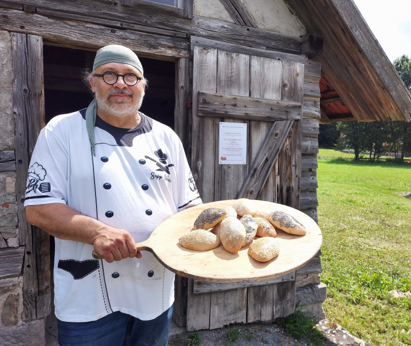 Mann pr&auml;sentiert Br&ouml;tchen auf einem Holzbrett
